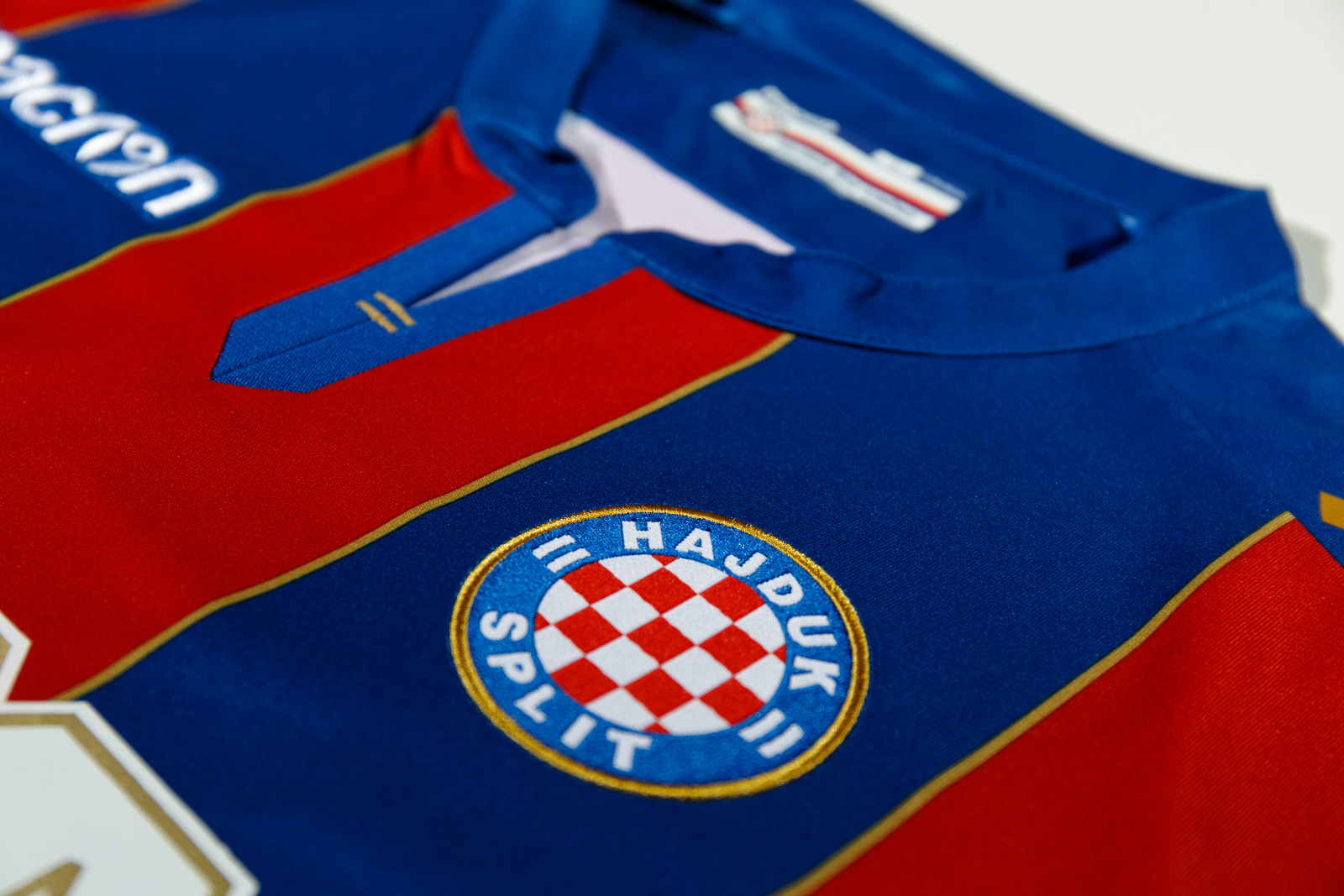 The Hajduk Split Away shirt 2017/18 has vertical red and blue bands with  gold details. The Macron logo stands out in white on the top right-hand  side of, By Macron